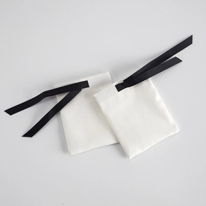 Close-up of white fabric jewelry pouch with black ribbed drawstring and fine stitching