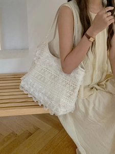 Close-up of white lace crochet shoulder bag showing intricate floral weave and wavy edges