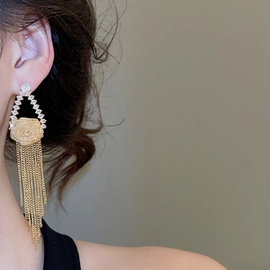 Detailed view of long gold tassel earrings with white zircon flowers worn by a model