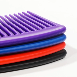 Dettaglio macro di pettini a denti larghi sovrapposti in viola blu rosso e nero