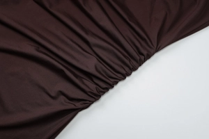 Gros plan sur la texture du tissu marron foncé froncé avec des détails de plis mats