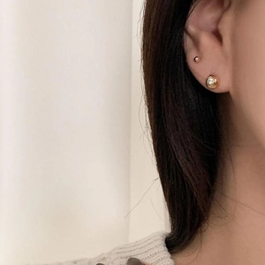 Detailed view of 18K gold cubic zirconia studs and mini ball earring on ear