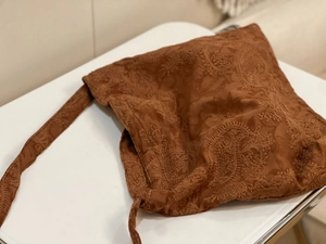 Close-up detail of vintage brown faux suede bag with intricate paisley floral embroidery