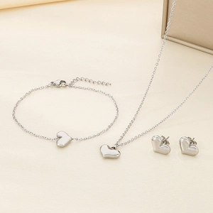 Close-up of silver heart-shaped jewelry set featuring necklace, bracelet, and stud earrings