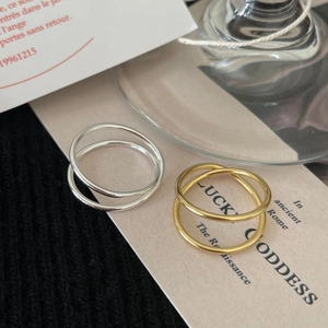 Close-up of minimalist silver and gold double-band rings on ivory cardstock background