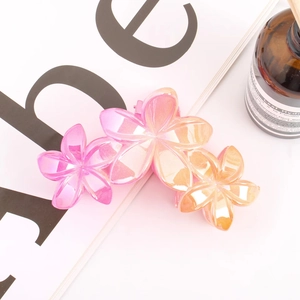 Close-up of triple flower claw clip with pink to orange gradient resin petals and spring