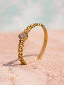 Detail of 18k gold plated NK chain bracelet with oval zircon clasp on beach sand