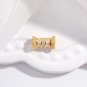 Macro d'une perle cylindrique dorée sertie de zircons blancs pour la création de bijoux