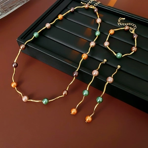 Detail of jewelry set with colorful beads and golden wavy chains on a black stand