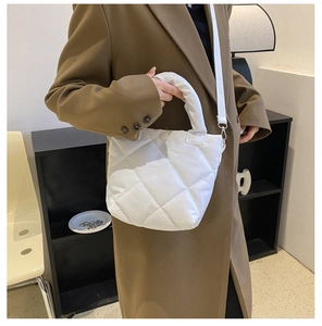 Close-up of white quilted bucket bag with grid stitching and detachable strap