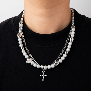 Detail of silver double-layered necklace with pearls and cross pendant on model