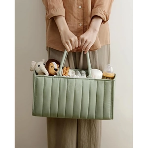 Close-up of green quilted diaper tote bag showing spacious storage for baby bottles