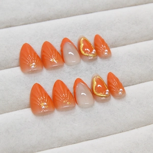 Orange and white gradient press-on nails with 3D shell texture and gold heart accents