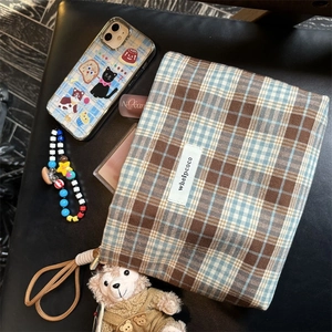 Detail view of plaid fabric organizer bag in brown and blue on leather surface