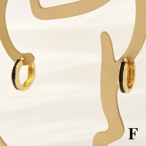 Close-up of 18K gold-plated round hoop earrings with black enamel on a gold display stand