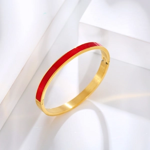 Detailed shot of red enamel finish on a gold stainless steel bangle set on a stone block