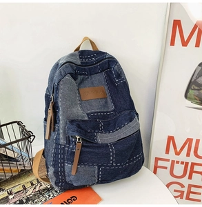 Detail of vintage patchwork denim backpack with blue denim fabric and brown leather puller