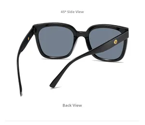 Detail view of large square black sunglasses with golden metal hinges and gray lenses