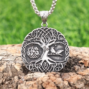 Detail of Viking Tree of Life pendant with raven relief on rustic wood surface