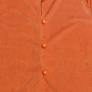 Détail macro du cardigan court en maille orange montrant la texture et les boutons