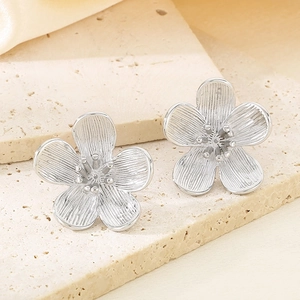 Detailed view of silver petal stud earring with brushed texture and central pearl detail