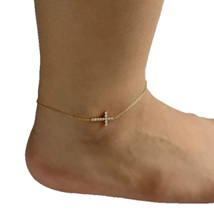 Elegant gold stainless steel cross anklet with sparkling zircon stones on female foot