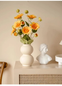 Minimalist beige ceramic vase with yellow sunflower bouquet on a rustic sideboard decoration