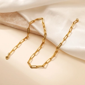 Elegant gold titanium steel chain necklace with rectangular links on white silk and marble