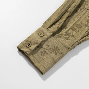 Detailed view of olive green jacquard shirt cuff with textured fabric and two resin buttons