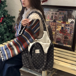 Detailed view of dark grey faux shearling tote bag with white polka dots on a wooden bench