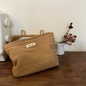 Detail of woven fabric handbag with grain pattern and 'Simple Wish' label on wood