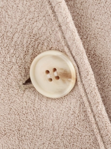 Gros plan du bouton marbré et du tissu beige à gros grains sur la veste en peau