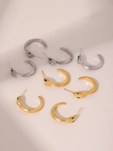 Détail macro de boucles d'oreilles serpent avec écailles et yeux en zircon vert