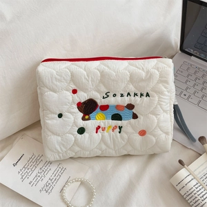 Close-up of white heart-quilted puppy embroidery makeup bag with red zipper detail