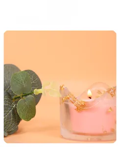 Gros plan d'une bougie rose parfumée dans un verre à feuille d'or avec lumière douce