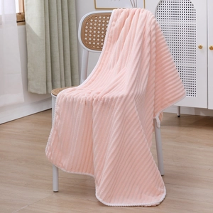 Detailed texture of pink striped coral fleece blanket draped on a white rattan chair