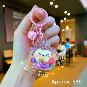 Detail shot of a liquid sand glitter keychain showing size dimensions and a pink bell