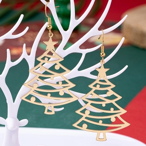 Macro shot of gold hollow Christmas tree earrings hanging on a white antler stand