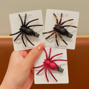Detailed view of three glitter spider hair clips in black, orange, and pink for Halloween