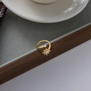 Detail of gold sun-shaped ring with zircon stones on a gray velvet jewelry tray