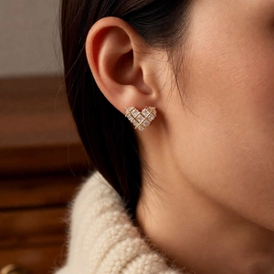 Detail shot of heart-shaped gold studs with square-cut cubic zirconia on model