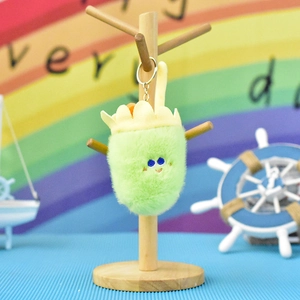 Close-up of cute green fuzzy plush keychain with embroidered face and yellow rim