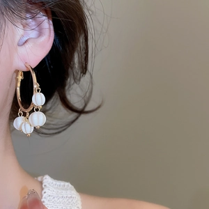 Detail shot of golden metal hoop earrings featuring five white striped resin bead charms