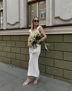 Détail de la robe longue en crochet blanc avec texture tricotée et sac tissé assorti