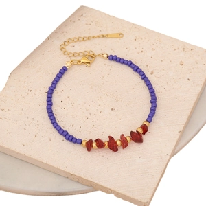 Bohemian style beaded bracelet with purple beads and red natural stones on a stone background