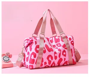 Detailed close-up of pink leopard print travel bag with golden hardware and nylon handles