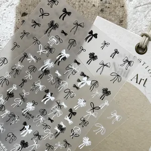 Close-up of black and white bow nail art stickers featuring hand-drawn style patterns