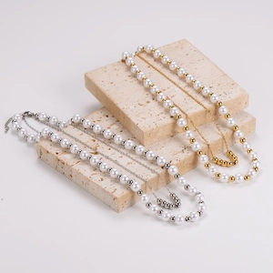 Elegant layered gold and silver pearl necklaces displayed on premium travertine stone