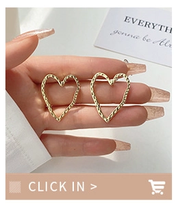 Close-up of gold hollow heart stud earrings showing hammered texture and size on hand
