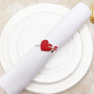 Detailed view of a red heart-shaped napkin ring with rhinestones on a white fabric napkin